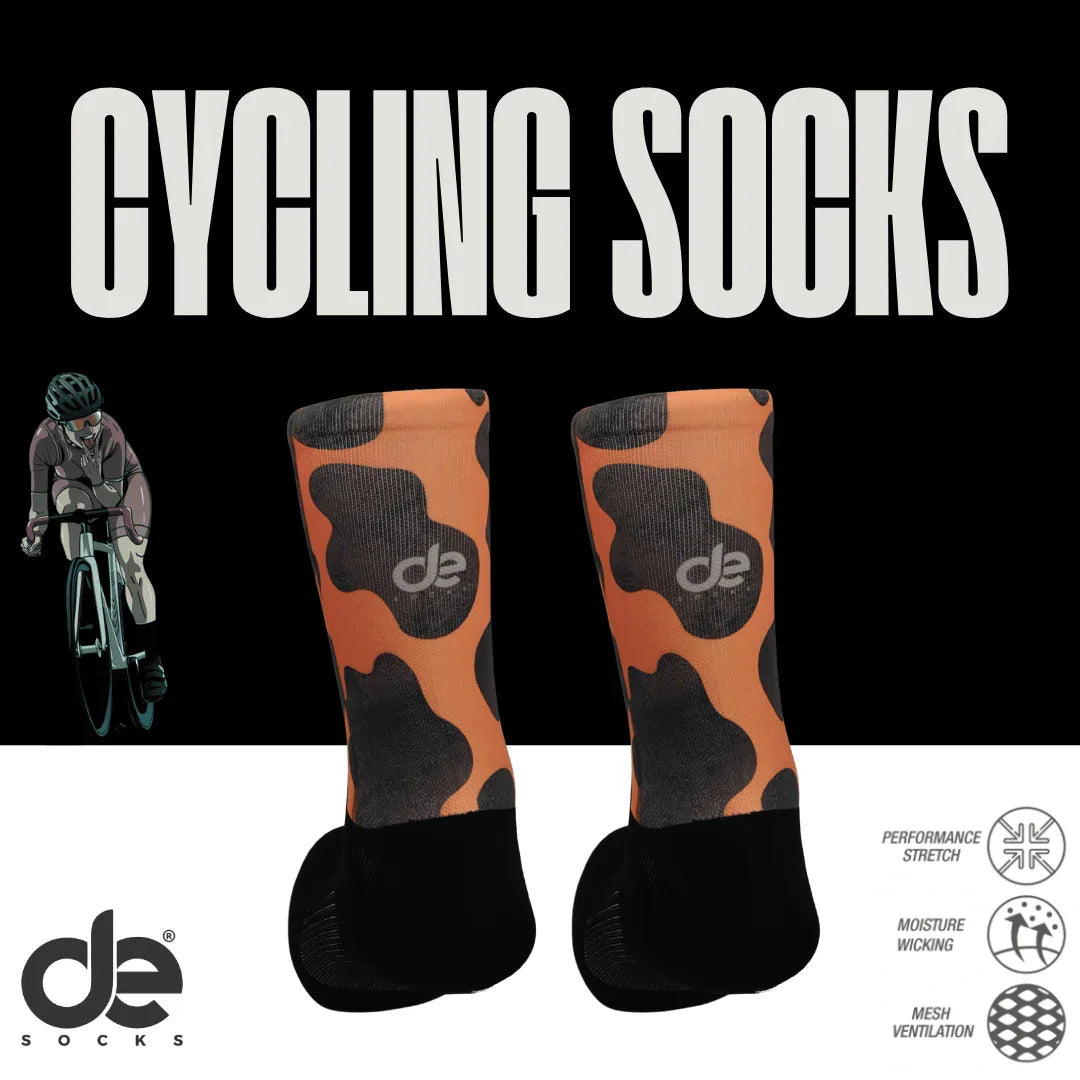 Cow ποδηλατικές κάλτσες-αναπνέουσες με πορτοκαλί-μαύρο σχέδιο και λογότυπο de. Με διαπνοή, stretch και απορρόφηση υγρασίας για ποδηλάτες.